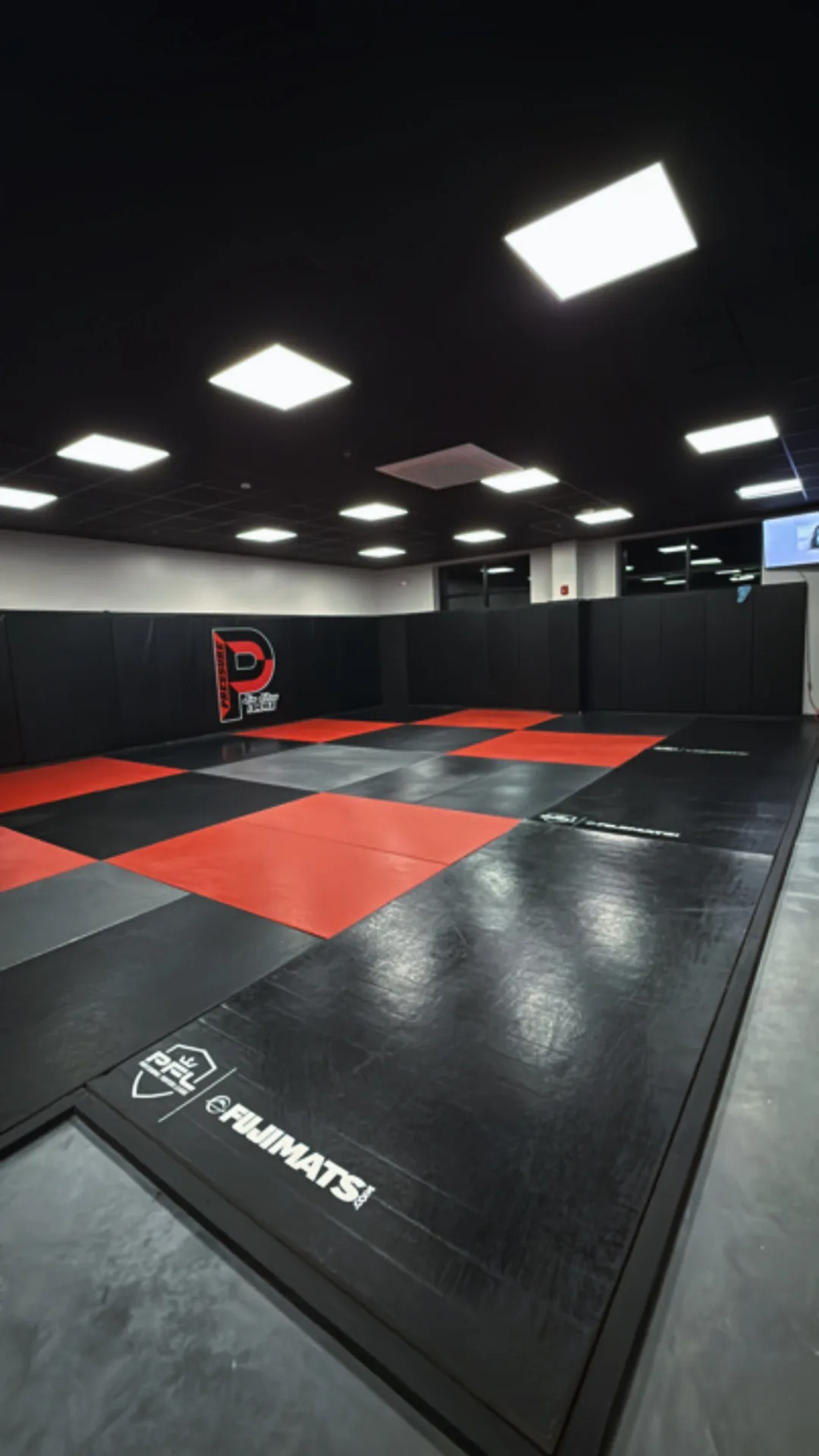 Pressure academy mat floor in red and black with the Pressure logo on the wall padding