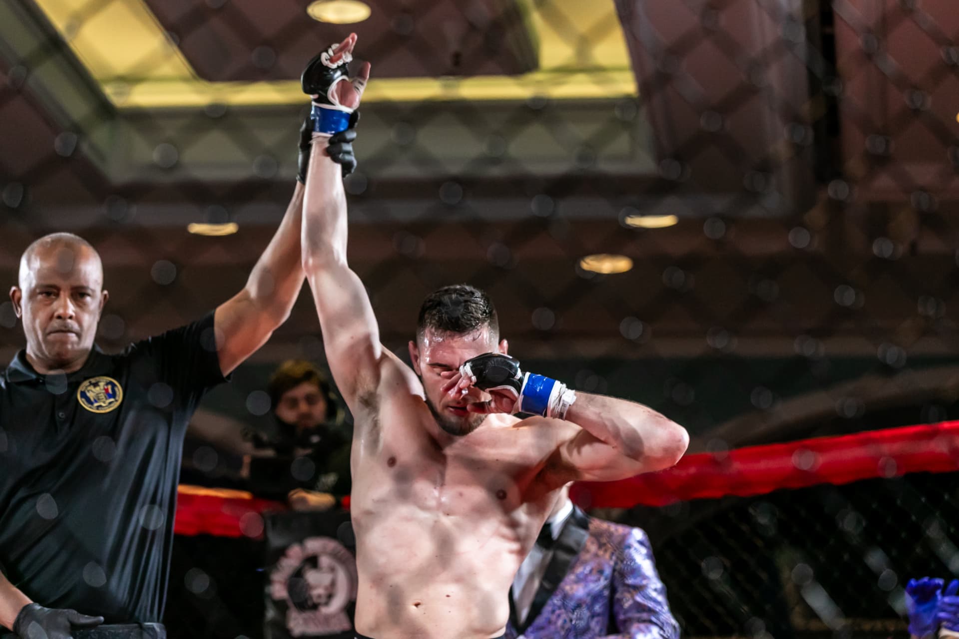 Fighter celebrating with his arm raised by the referee after an amateur MMA win